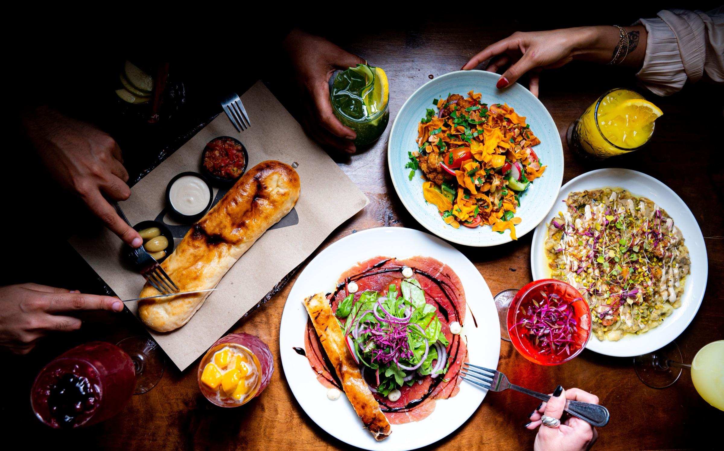 Shared plates, drinks, and bread on a table, representing flexible food tracking and calm calorie awareness