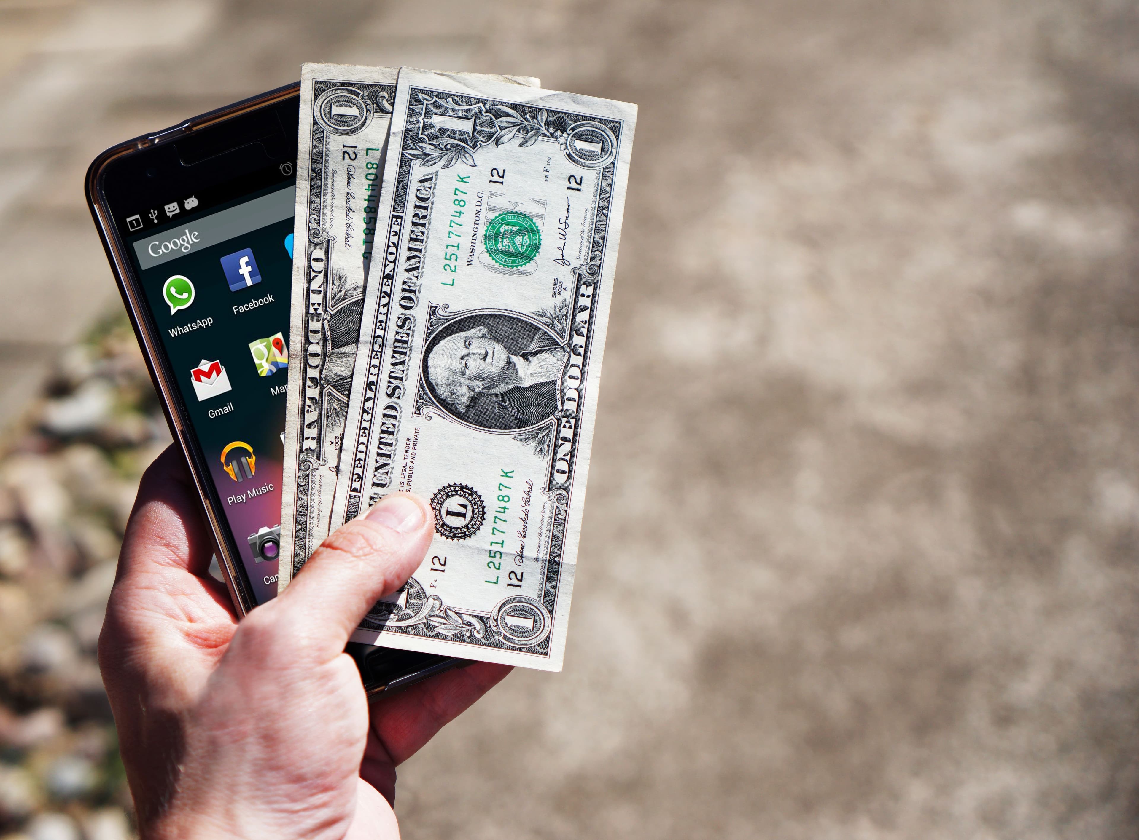 A hand holding a phone and dollar bills, representing movement turning into digital value