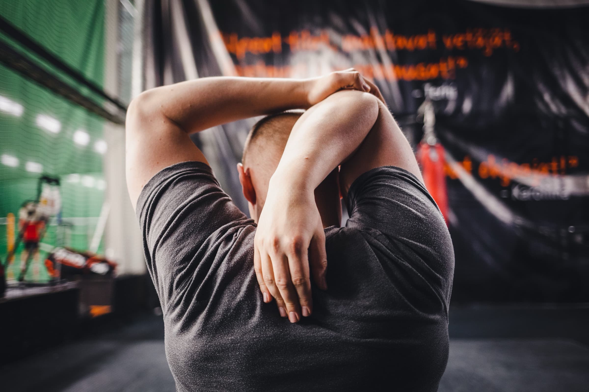 A person stretching their shoulders in a gym, representing flexibility and mobility work